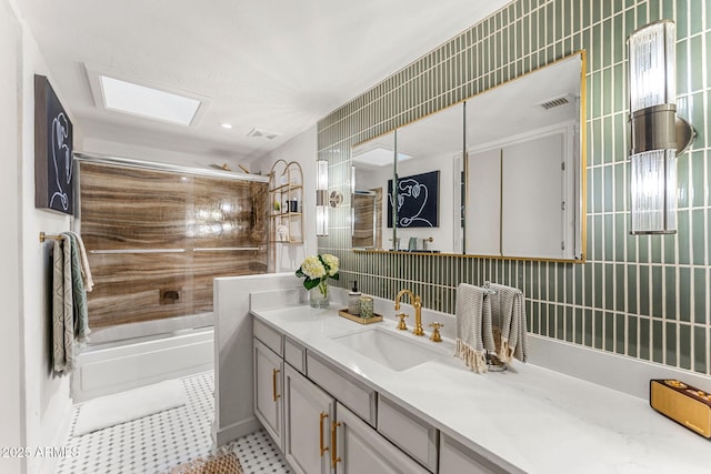 bathroom with combined bath / shower with glass door, vanity, a skylight, and tile patterned flooring