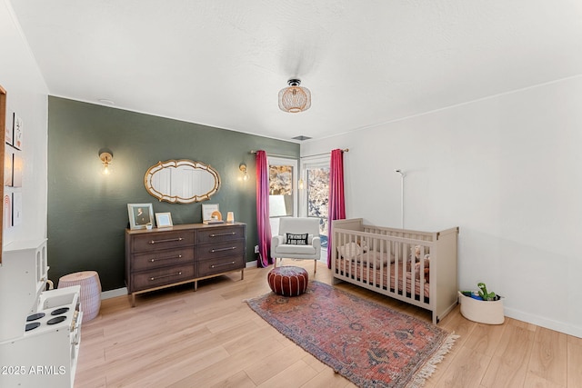 bedroom featuring light hardwood / wood-style flooring and a crib