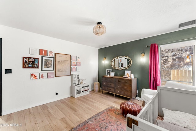 bedroom with hardwood / wood-style floors and a crib