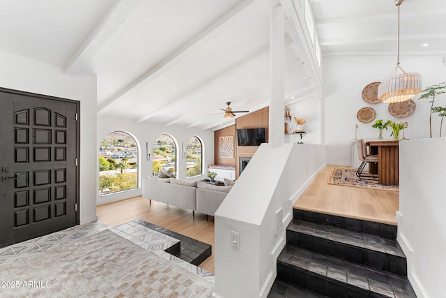 entrance foyer featuring ceiling fan with notable chandelier, hardwood / wood-style floors, and lofted ceiling with beams