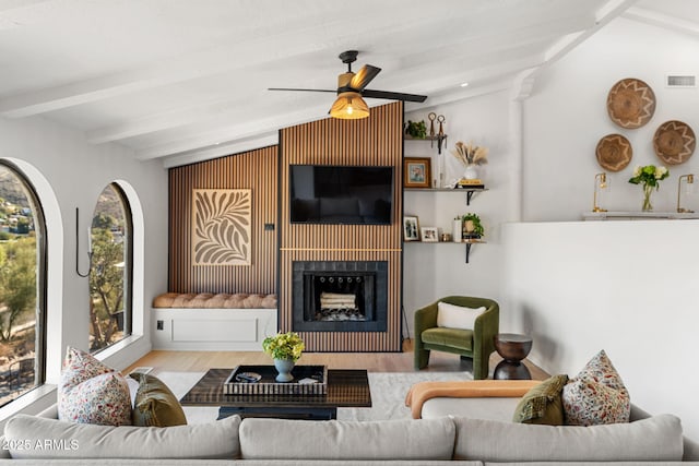 living room featuring ceiling fan, a wealth of natural light, light hardwood / wood-style flooring, and lofted ceiling with beams