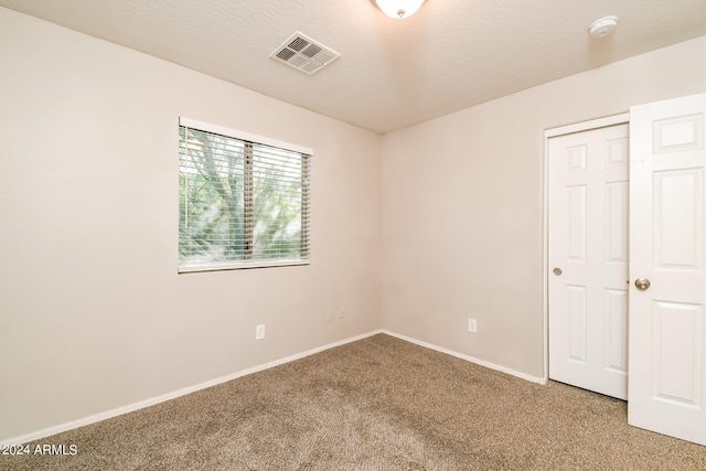 empty room featuring a textured ceiling and carpet flooring