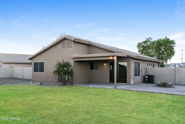 rear view of property with central air condition unit, a patio, and a lawn