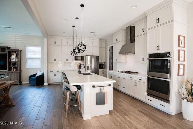 4226 E Coconino Pl, Chandler, AZ 85249 - kitchen with stainless steel appliances, a sink, wood finished floors, wall chimney range hood, and light countertops