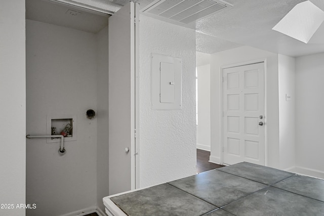 interior space with a skylight, hookup for a washing machine, and electric panel