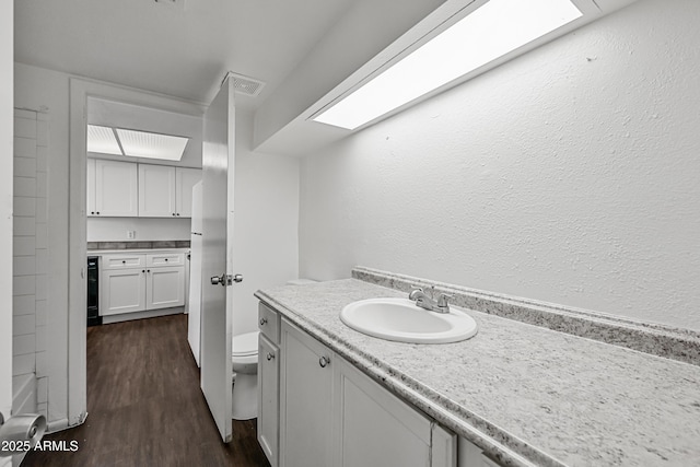 bathroom featuring toilet, hardwood / wood-style flooring, beverage cooler, and vanity