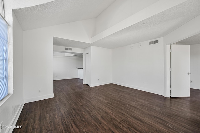 unfurnished living room featuring a textured ceiling, vaulted ceiling, and dark wood-type flooring