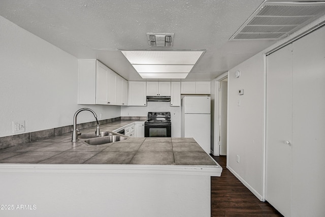 kitchen with white fridge, black electric range oven, tile counters, sink, and white cabinetry