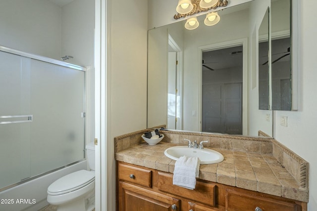 full bathroom with vanity, bath / shower combo with glass door, and toilet