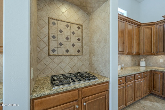 kitchen with tasteful backsplash, light stone countertops, and stainless steel gas stovetop