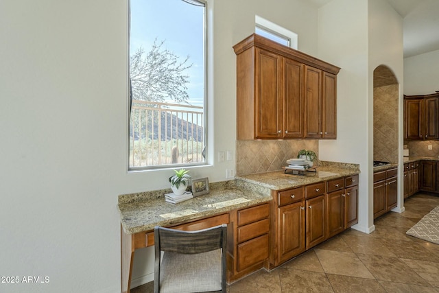 kitchen featuring tasteful backsplash, light tile patterned flooring, and light stone counters