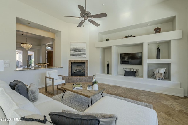 living room featuring a tiled fireplace, built in features, and ceiling fan