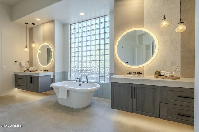 bathroom with tile walls, a towering ceiling, vanity, a bath, and tile patterned floors