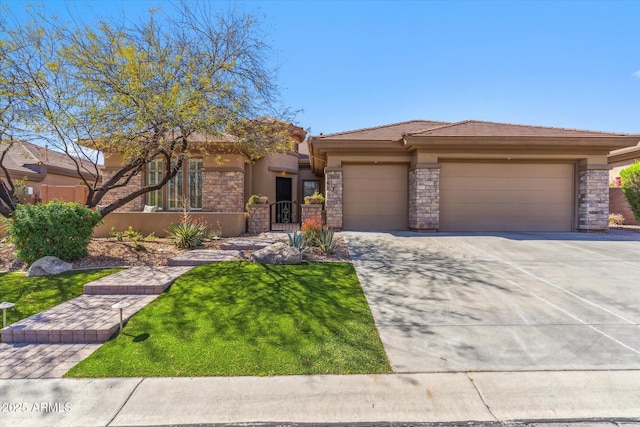 prairie-style home with driveway, stucco siding, a front lawn, stone siding, and a garage