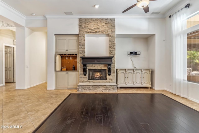 unfurnished living room with a ceiling fan, baseboards, light wood-style flooring, a fireplace, and crown molding