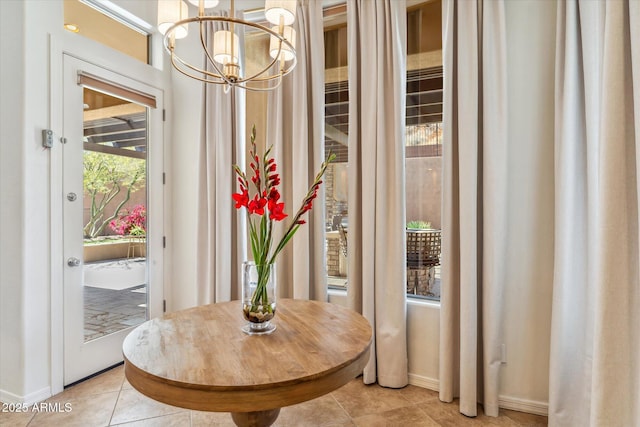 doorway with a chandelier, light tile patterned floors, and baseboards