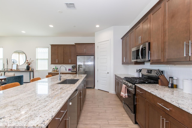 kitchen with light stone counters, sink, light hardwood / wood-style flooring, and stainless steel appliances