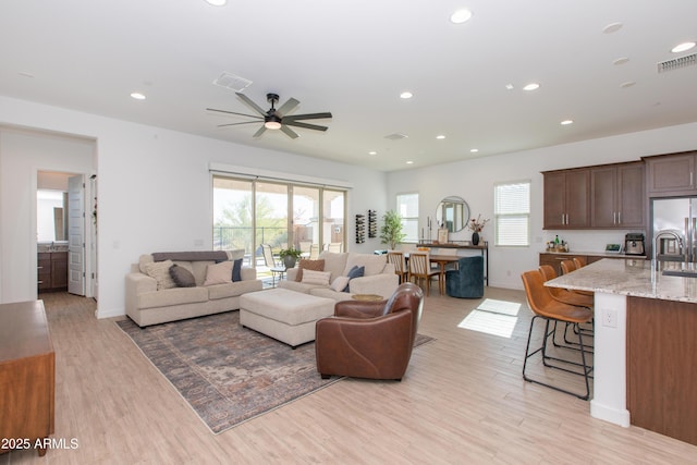 living room featuring sink, light hardwood / wood-style flooring, and ceiling fan