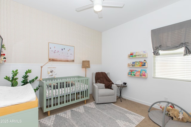 carpeted bedroom featuring ceiling fan and a nursery area