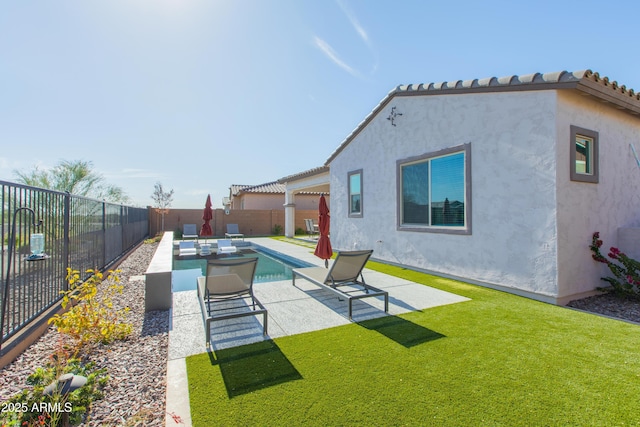 rear view of house with a fenced in pool, a yard, and a patio