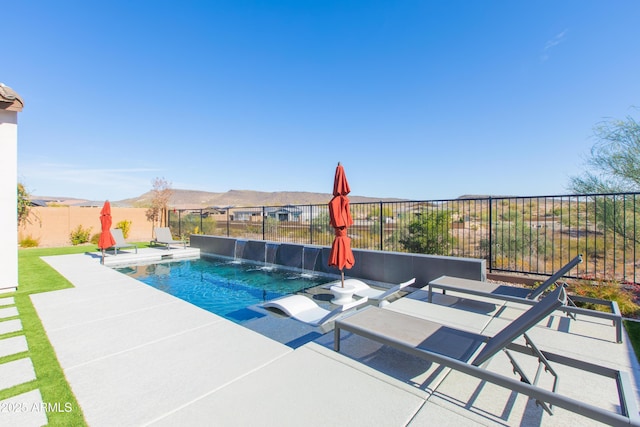 view of pool featuring a mountain view, pool water feature, and a patio