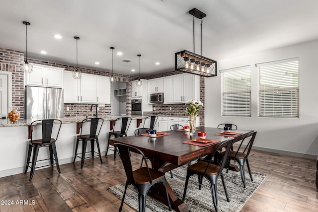 dining space with dark wood-type flooring and brick wall