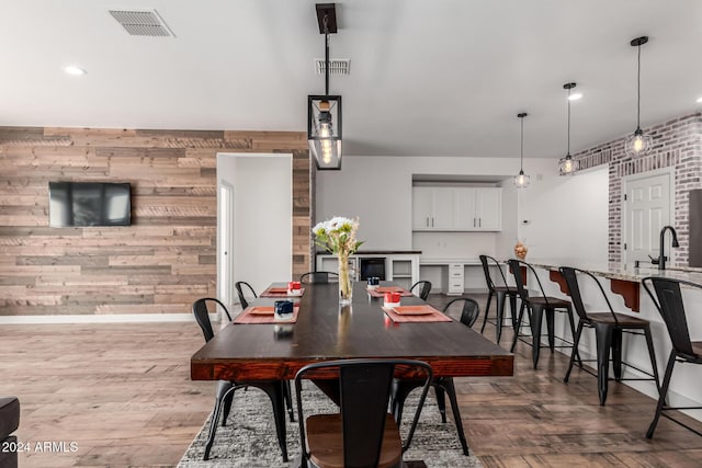 dining room featuring light hardwood / wood-style floors, sink, and wooden walls