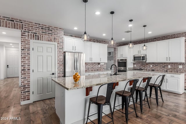 kitchen with white cabinetry, a spacious island, decorative light fixtures, and appliances with stainless steel finishes