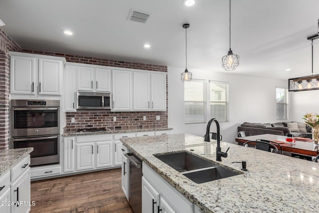 kitchen featuring stainless steel appliances, white cabinetry, hanging light fixtures, and sink