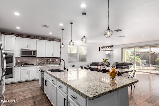 kitchen with appliances with stainless steel finishes, a kitchen island with sink, sink, decorative light fixtures, and white cabinets