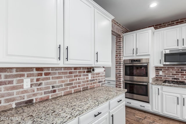 kitchen with light stone countertops, white cabinetry, and stainless steel appliances