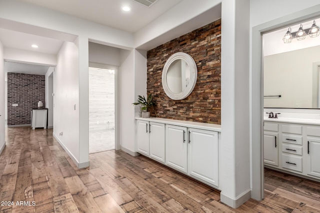 hall featuring sink, brick wall, and light wood-type flooring