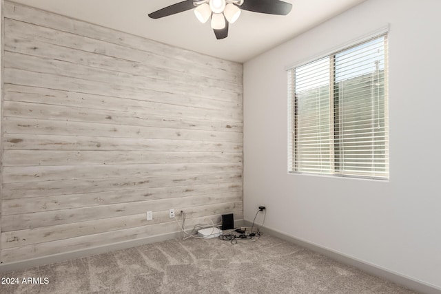 carpeted spare room featuring ceiling fan and wooden walls