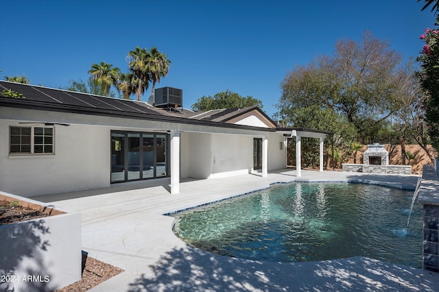 outdoor pool with a patio area, an outdoor stone fireplace, and cooling unit