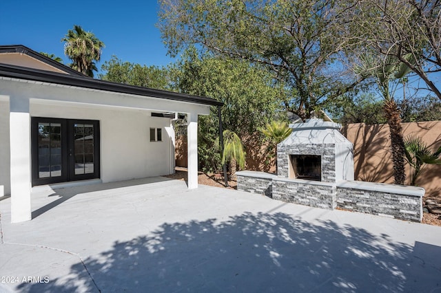 view of patio / terrace featuring an outdoor stone fireplace, fence, and french doors