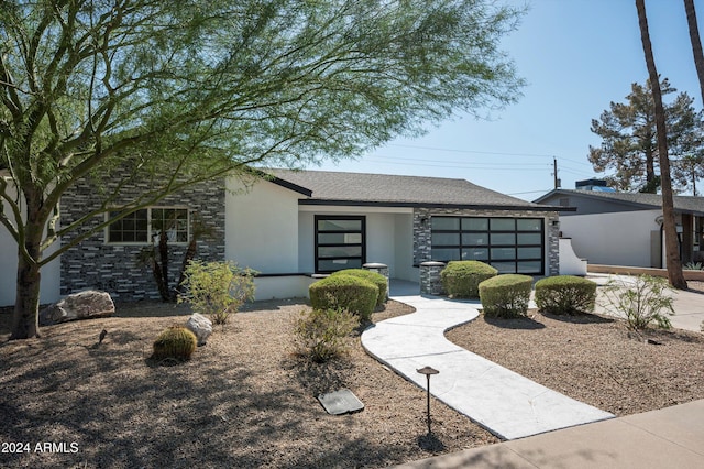 view of front of property featuring stone siding, a shingled roof, and stucco siding