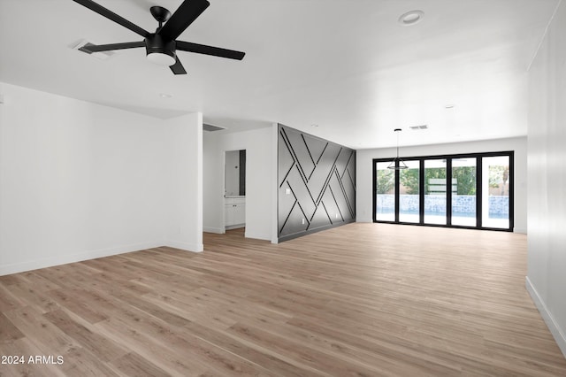 unfurnished room featuring light wood finished floors, visible vents, baseboards, and ceiling fan