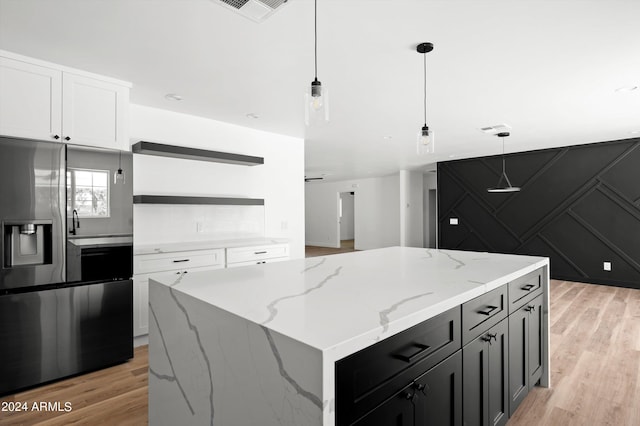 kitchen featuring light stone counters, open shelves, hanging light fixtures, white cabinets, and stainless steel fridge