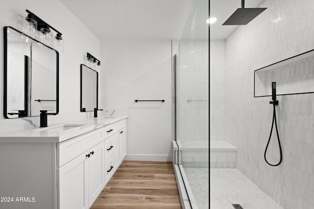 bathroom with wood finished floors, double vanity, a sink, and walk in shower