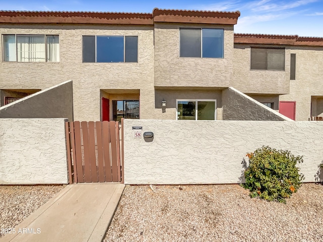 view of front of house featuring stucco siding, fence, and a gate