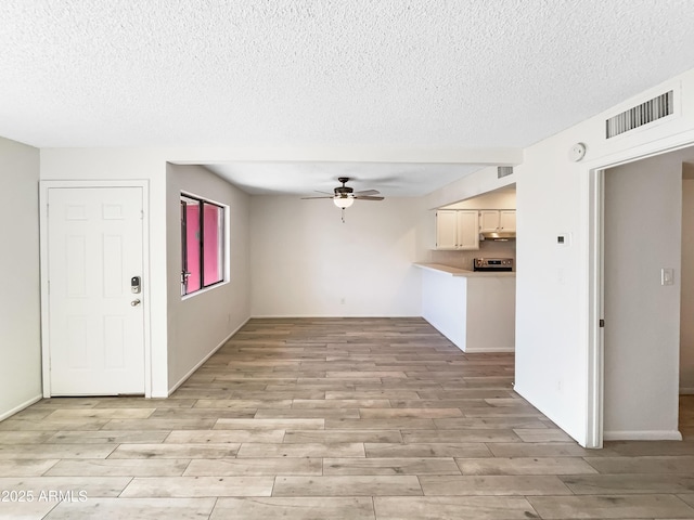 unfurnished living room featuring a textured ceiling, visible vents, light wood finished floors, and ceiling fan