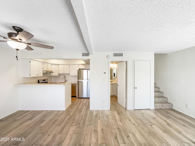 unfurnished living room with a sink, visible vents, a ceiling fan, and light wood finished floors