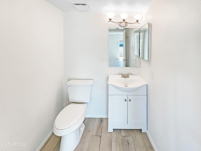 bathroom with visible vents, toilet, wood finished floors, baseboards, and vanity