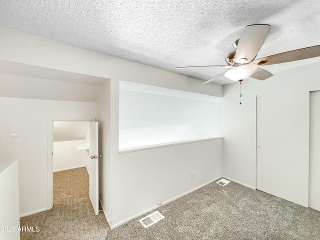 carpeted spare room featuring ceiling fan, baseboards, visible vents, and a textured ceiling