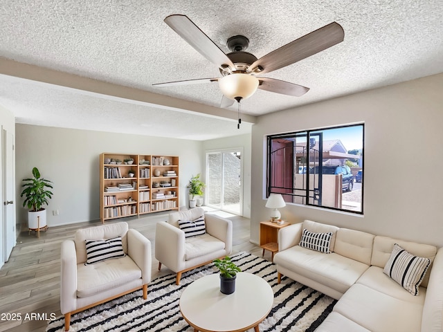 living room with a ceiling fan, wood finished floors, and a textured ceiling