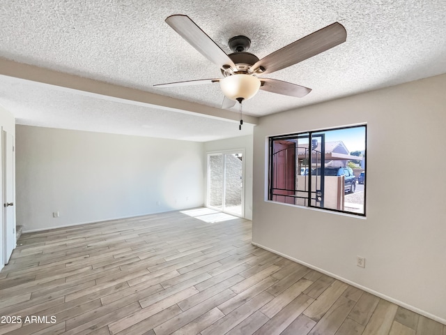 spare room with a textured ceiling, light wood-type flooring, and a ceiling fan