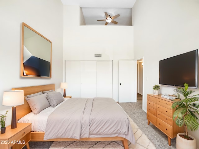 bedroom featuring light carpet, visible vents, a high ceiling, and a closet