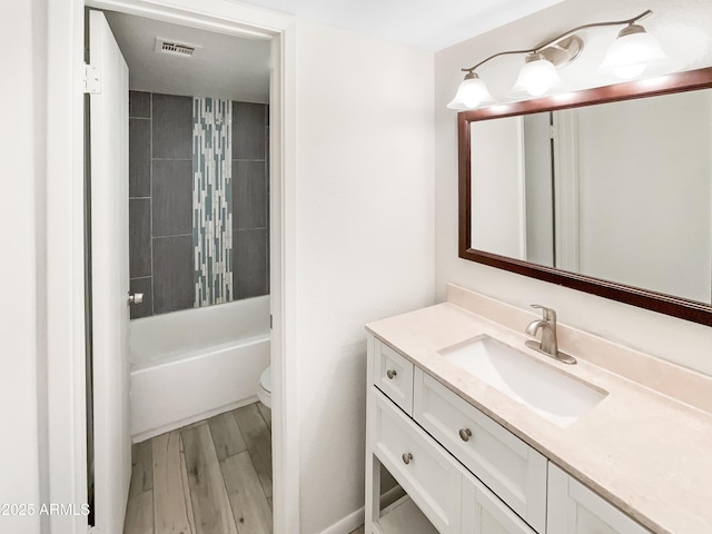 bathroom with vanity, wood finished floors, visible vents, toilet, and shower / bathtub combination