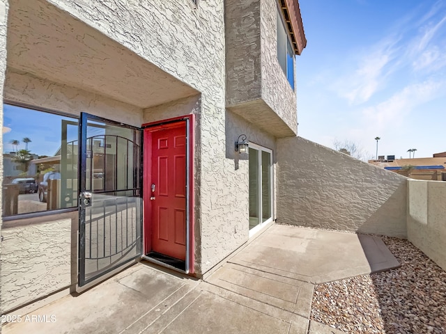 doorway to property featuring stucco siding and fence