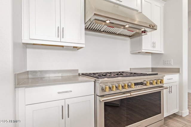 kitchen featuring light countertops, light wood-style flooring, white cabinetry, high end range, and extractor fan